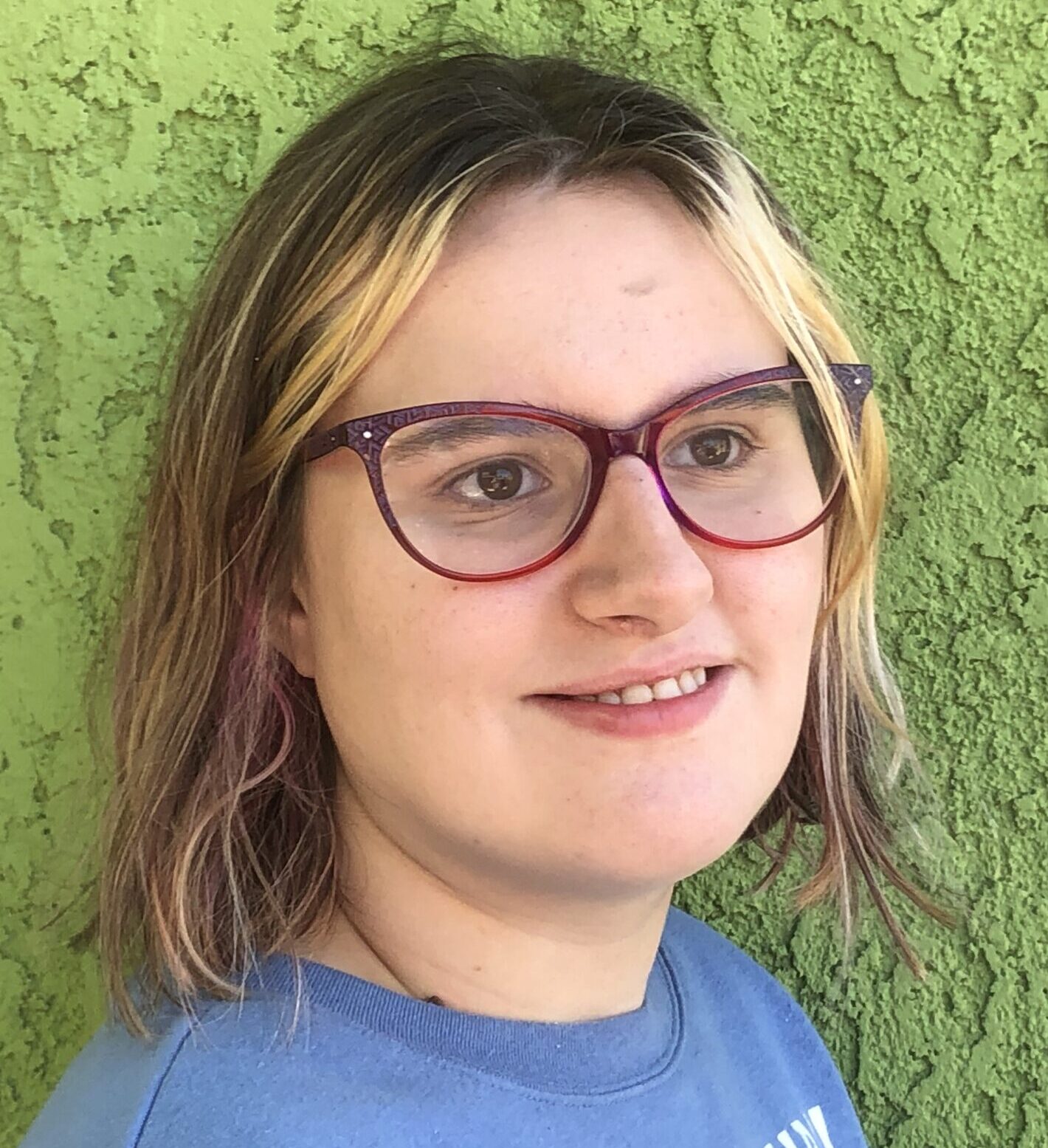 Pretty young woman with dark hair, blonde highlights, big, fashionable glasses and a terrific smile. She is Chistina, one of our Special Eats Special Team members.