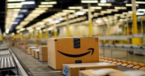 Amazon conveyor line. A box with a large smile graphic stamped on it is rolling down the line.