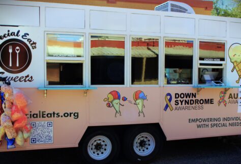 Special Eats Sweets Truck decorated with cartoon treats and awareness ribbons for Down Syndrome and Autism, promoting employment for individuals with special needs.